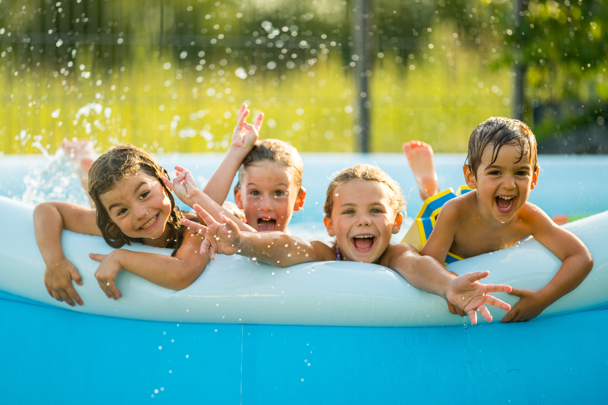 Four happy young kids in swimming pool